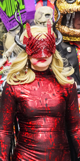 A demonic lady in a sparkly red mask and dress.